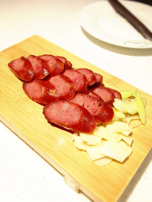 以生蒜片和大蔥作伴碟，夾著烤香腸來吃很match