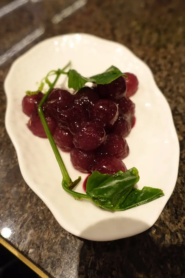 半球形的冬瓜以藍莓醬醃製，整齊放在碟子上，並以葉子點綴，看起來好像提子！