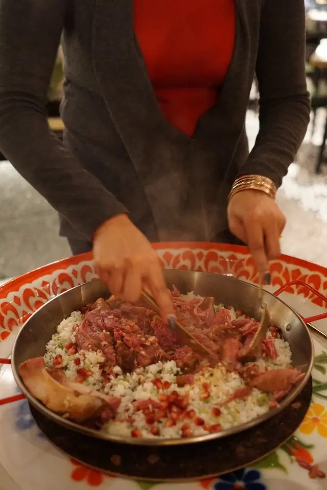 原隻豬手慢煮至軟稔化皮,置放在鋪上紅石榴籽的菜飯之上,由師傅加上甜麵醬即席拌勻。