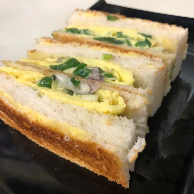 一碟總共分為三件,細心睇,原來一件蔥花蛋治係有四部份組成,抵免各有一塊搽上牛油嘅超薄多士,中間夾有一塊白方包,及主角蔥花炒蛋。一啖咬落蔥花味濃郁,喜愛食蔥嘅朋友一定唔可以錯過,另外多士夾嘅方包又是另一種有趣口感